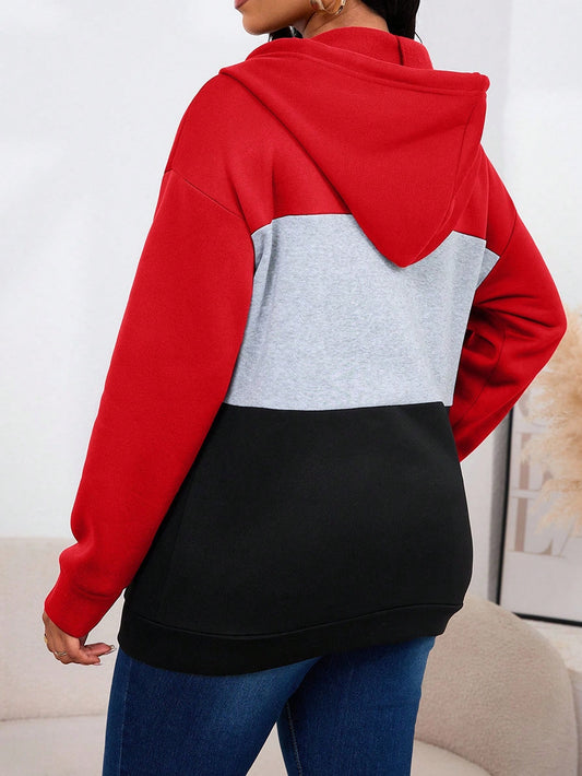 Person wearing a red, gray, and black color-blocked hoodie with a white background
